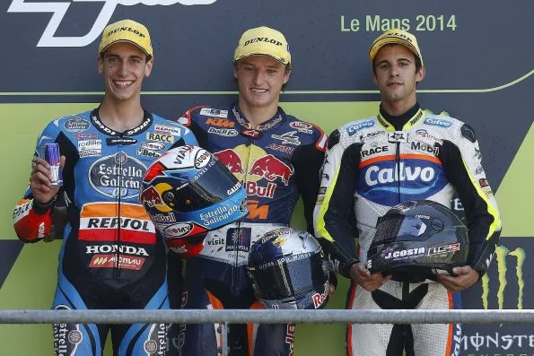 Jack Miller winning the Moto3 race at the 2014 French Grand Prix in Le Mans, standing on the podium in Red Bull KTM Ajo leathers flanked by Álex Rins and Isaac Viñales.
