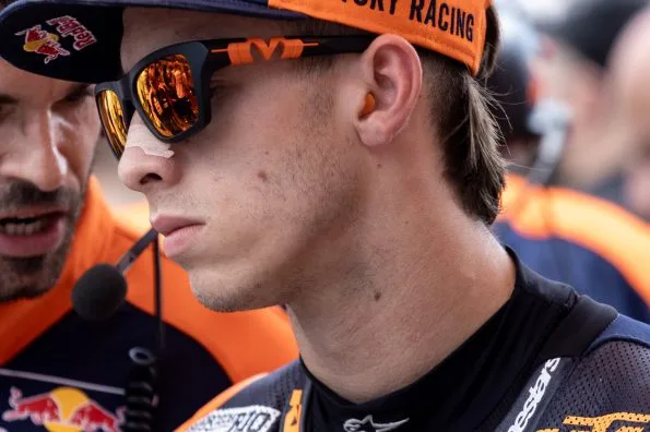Pedro Acosta in Red Bull KTM Factory Racing leathers and cap, wearing reflective sunglasses, photographed in the paddock at the 2025 Italian motorcycle Grand Prix.