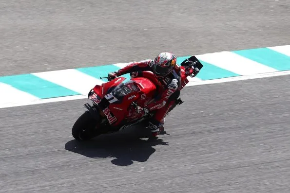 Pedro Acosta cornering his red Red Bull GASGAS Tech3 KTM, knee down and leaning into a left-hand turn, at the 2024 Malaysian motorcycle Grand Prix.
