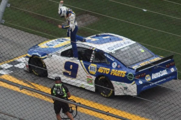 Chase Elliott standing on the roof of his No. 9 NAPA Auto Parts Chevrolet with an arm raised, celebrating, in 2020.