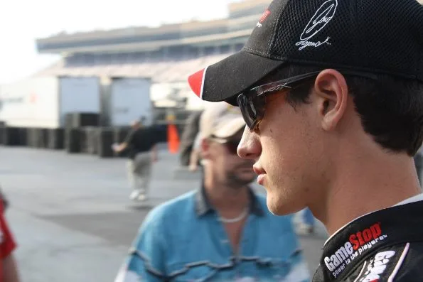Joey Logano in a GameStop-liveried race suit and cap walking out to his car for qualifying at Atlanta in 2009.